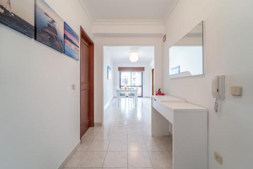 - un couloir avec des murs blancs et du carrelage blanc dans l'établissement Quarteira Beach - 2 D by HelloVacations, à Loulé