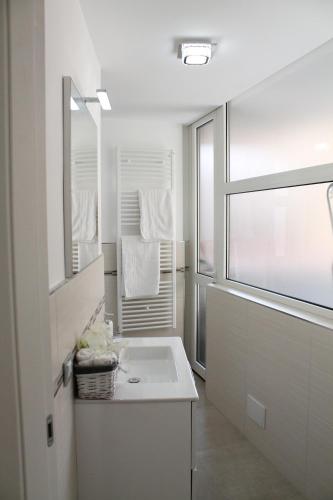 a white bathroom with a sink and a window at Da Mariella case vacanze con terrazzo in Sanremo