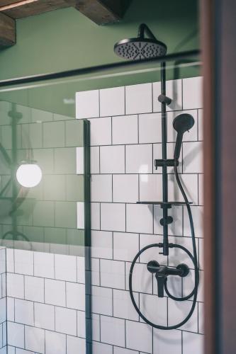 a shower in a bathroom with white tiles at Kardamom Studio Apartman in Szigliget