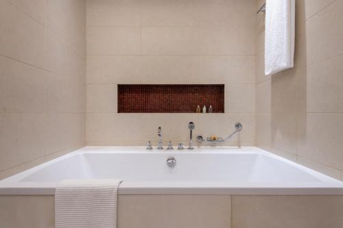 a white bath tub in a white bathroom at Fraser Suites Doha in Doha