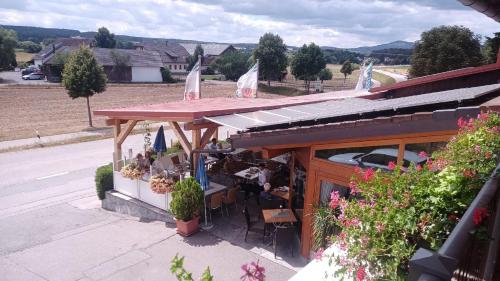 um restaurante com toldo e mesas e cadeiras numa rua em Landgasthof Schmidbauer em Nittenau