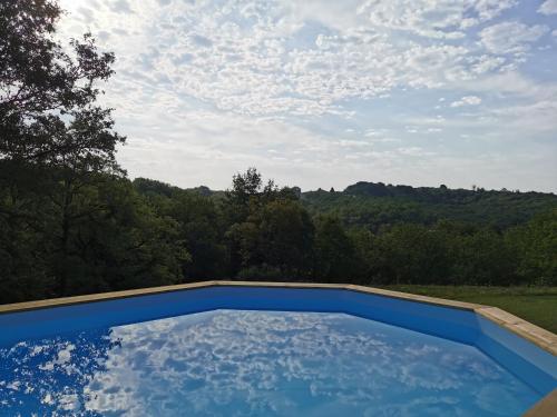 a blue swimming pool with a view of the mountains at Maison typique périgourdine avec piscine in Paulin