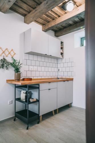 a kitchen with white cabinets and a wooden counter top at Kardamom Studio Apartman in Szigliget