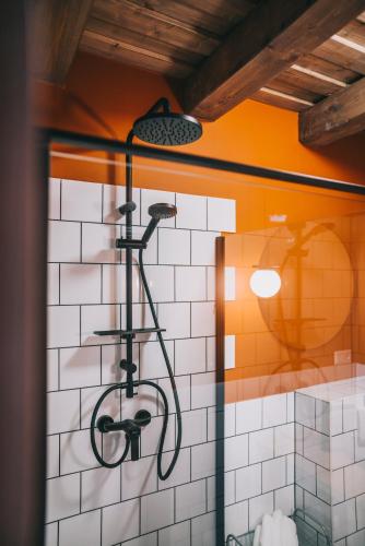 a shower in a bathroom with white tiles at Kardamom Studio Apartman in Szigliget