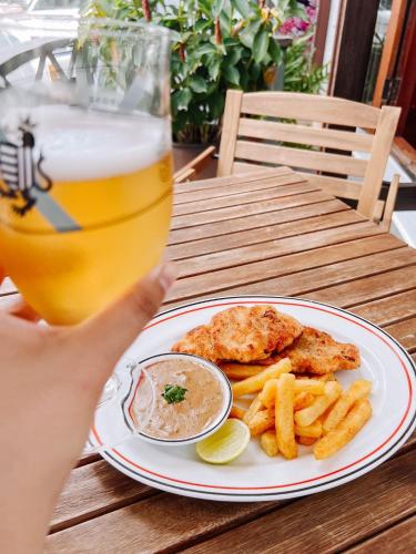 a person holding a glass of beer and a plate of food at Le Charme Vientiane Hotel in Vientiane
