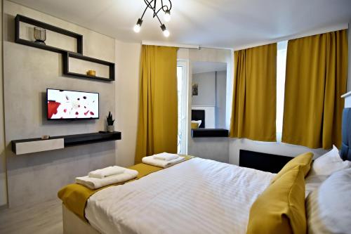 a bedroom with a bed with yellow curtains and a tv at Apartment Orpheus in Velingrad
