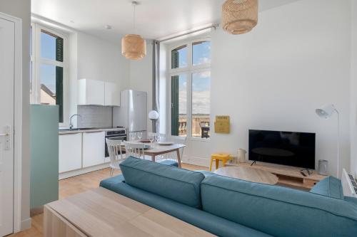 a living room with a blue couch and a kitchen at Vue mer au coeur du Croisic in Le Croisic