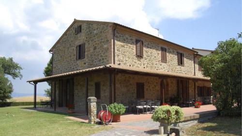 a stone building with tables and chairs in front of it at Agriturismo Casale trieste in Laiatico