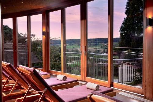 a room with chairs and a balcony with windows at Ayurveda Resort MANDIRA in Bad Waltersdorf