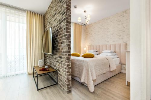 a bedroom with a brick wall and a bed with yellow pillows at Happy Stay Chlebova Residence in Gdańsk