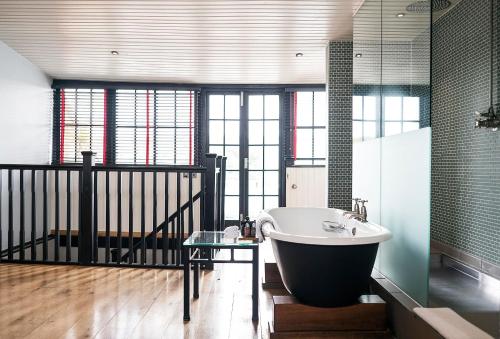 Hotel du Vin Henley في هينلي على نهر التايمز: حمام مع حوض استحمام وطاولة زجاجية