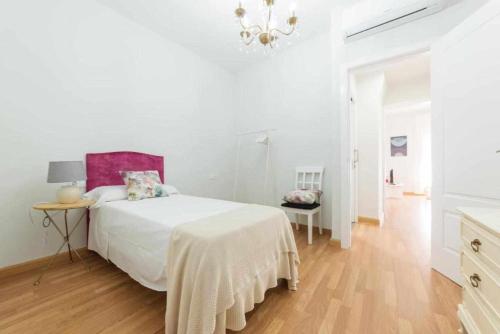 Habitación blanca con cama y lámpara de araña. en Casa Angeline Verde 3 By KubiK, en Cáceres