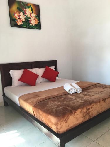 a bedroom with a bed with red and white pillows at Wahyu Homestay 1 in Nusa Lembongan