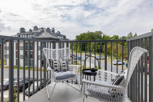 a balcony with two chairs and a table and a street at Seaside Apartment Wybrzeze Dziwnow in Dziwnów