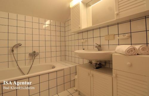 a white tiled bathroom with a sink and a bath tub at Apartment KATHREIN ski & spa in Bad Kleinkirchheim