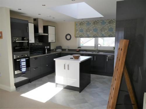 a kitchen with black cabinets and a white island at Driftwood in Kippford