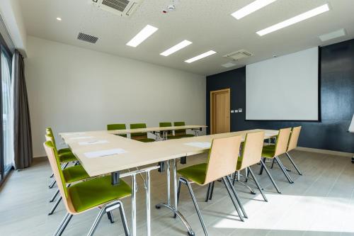 a conference room with a table and chairs and a screen at Casa Calfelor Kolping Timișoara in Timişoara