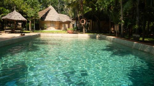 a swimming pool with blue water in front of a house at Eleven Pearl Boutique Hotel & Spa in Diani Beach