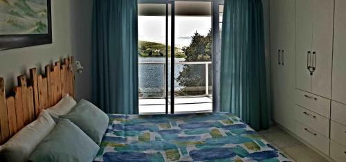 a bedroom with a bed and a window with a view at Black Rock Haven in Scottburgh