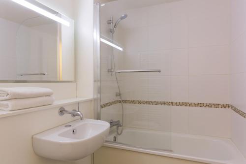 La salle de bains blanche est pourvue d'un lavabo et d'une douche. dans l'établissement Kyriad Annecy Nord - Epagny, à Metz-Tessy