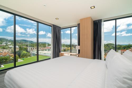 a bedroom with a large bed and large windows at Grand Kata VIP - Kata Beach in Kata Beach