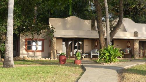 a white house with trees in front of it at Eleven Pearl Boutique Hotel & Spa in Diani Beach