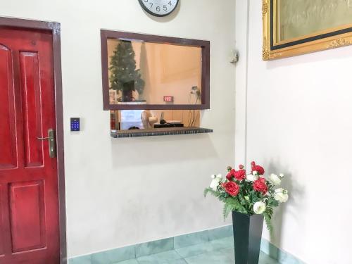 um vaso de flores sentado ao lado de uma porta vermelha em RedDoorz @ Jalan Gelanggang Remaja Waena Jayapura em Sentani