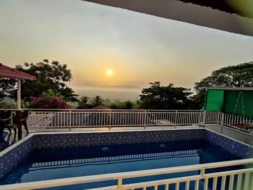 a swimming pool with a sunset in the background at WhiteHouse Homestay by Oxystays Hospitality in Alibaug