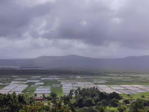 an aerial view of a field with mountains in the background at WhiteHouse Home stay by Oxystays in Alibaug