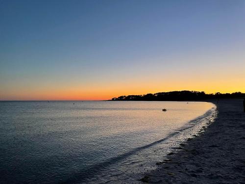 a beach with the sun setting in the background at Maison de vacances à Sarzeau à 5 min de la plage à pieds in Sarzeau