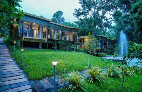 a house with a fountain in the yard at Kuruva Island Resort And Spa - By KABINI BREEZE, Wayanad in Mananthavady