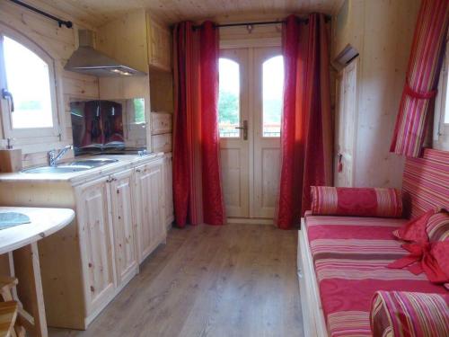 a kitchen with red curtains and a couch in a room at La Roulotte de Bourgogne in Brianny