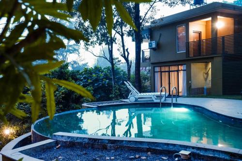 a swimming pool in front of a house at Kuruva Island Resort And Spa - By KABINI BREEZE in Mananthavady