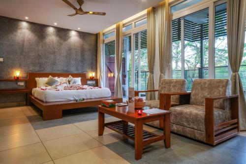 a bedroom with a bed and a couch and a table at Kuruva Island Resort And Spa - By KABINI BREEZE, Wayanad in Mananthavady