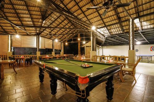 a pool table in a room with tables and chairs at Kuruva Island Resort And Spa - By KABINI BREEZE in Mananthavady