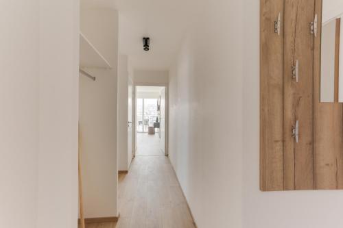 a hallway with white walls and a wooden door at Evancy La Marina Boulogne-sur-Mer in Boulogne-sur-Mer