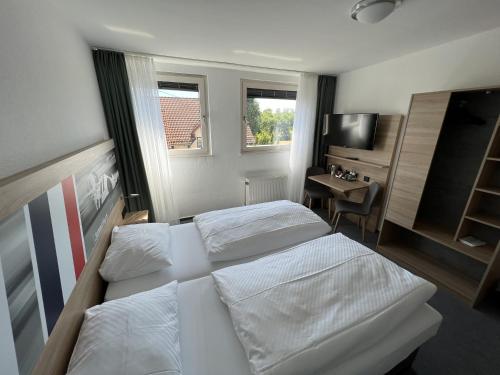 a bedroom with two beds and a desk and a television at Hotel Am Tiergarten in Nürburg