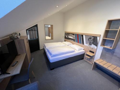 una camera con un letto e una televisione di Hotel Am Tiergarten a Nürburg