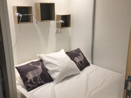 un lit avec deux oreillers dessus dans une chambre dans l'établissement Appartement rénové 7/8 pers, au calme avec balcon, parking et wifi inclus, au centre de la station - FR-1-346-307, à Arc 1800