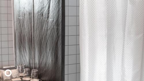 uma casa de banho com uma cortina de chuveiro e um espelho. em Center Hotels Klopp em Reykjavík