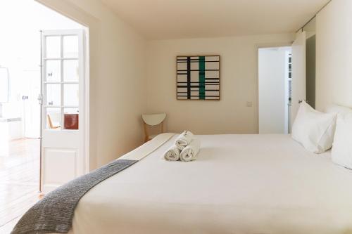 Un dormitorio con una gran cama blanca con zapatos encima. en Castelo Premium by Homing, en Lisboa