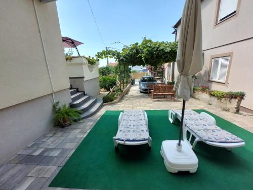 two beds and an umbrella on a green carpet at Apartman Lovre in Zadar