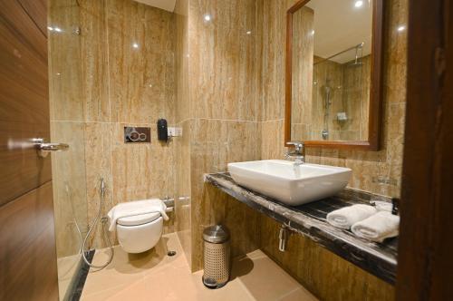 ein Badezimmer mit einem Waschbecken, einem WC und einem Spiegel in der Unterkunft Cygnett Park Meghna in Bongaigaon