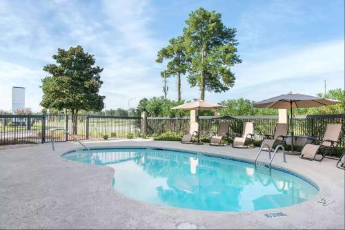 a swimming pool with chairs and umbrellas at Baymont by Wyndham Port Wentworth in Port Wentworth