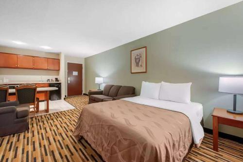 a hotel room with a bed and a living room at Baymont by Wyndham Port Wentworth in Port Wentworth