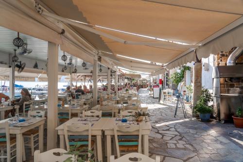 a restaurant with white tables and chairs and people sitting at Absolute Perdika Aegina in Perdika