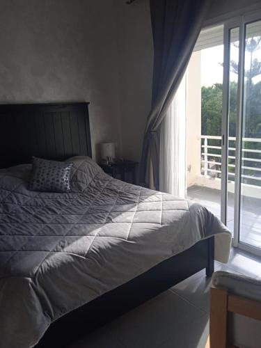 a bedroom with a bed and a large window at Sidi Rahal Villa avec piscine à 5min de la plage in Dar Hamida