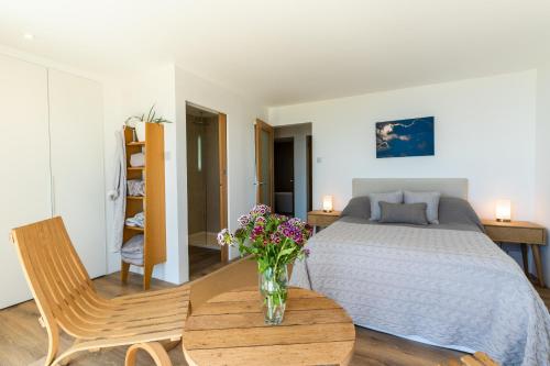 Un dormitorio con una cama y un jarrón de flores sobre una mesa. en Finest Retreats - Avalon Sea Views, en Downderry