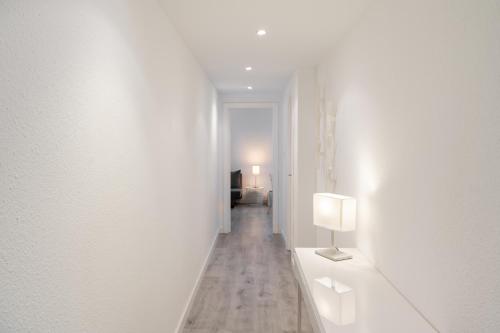 un couloir blanc avec une lampe sur un mur blanc dans l'établissement Apartamento al lado de la Romareda, à Saragosse