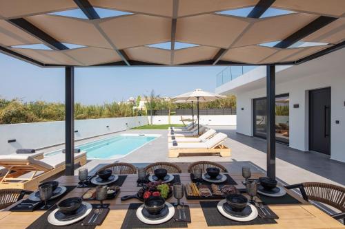 an outdoor dining area with a table and chairs and a pool at Horizon Luxury Villa in Chania Town